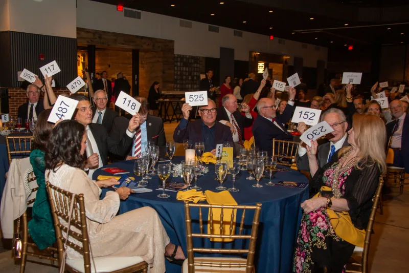 Guests raising auction paddles at the Spirit of Saint Nicholas Ball