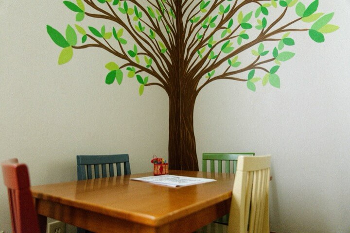 Children’s activity room with a painted tree and colorful chairs